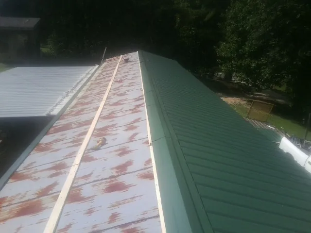 Old rusted panels beside newly installed green metal roofing — Wind Damage Roof Repair by Roofing Brothers in Cowan