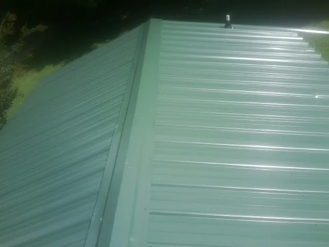 New green metal panels meeting at the ridge of a roof — Flat Roof Repair work by our crew in Cowan