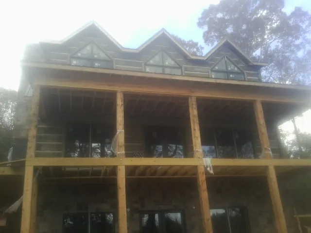 Dormers and porch framing on a large log home under construction — Roof Coating work by our crew in Cowan