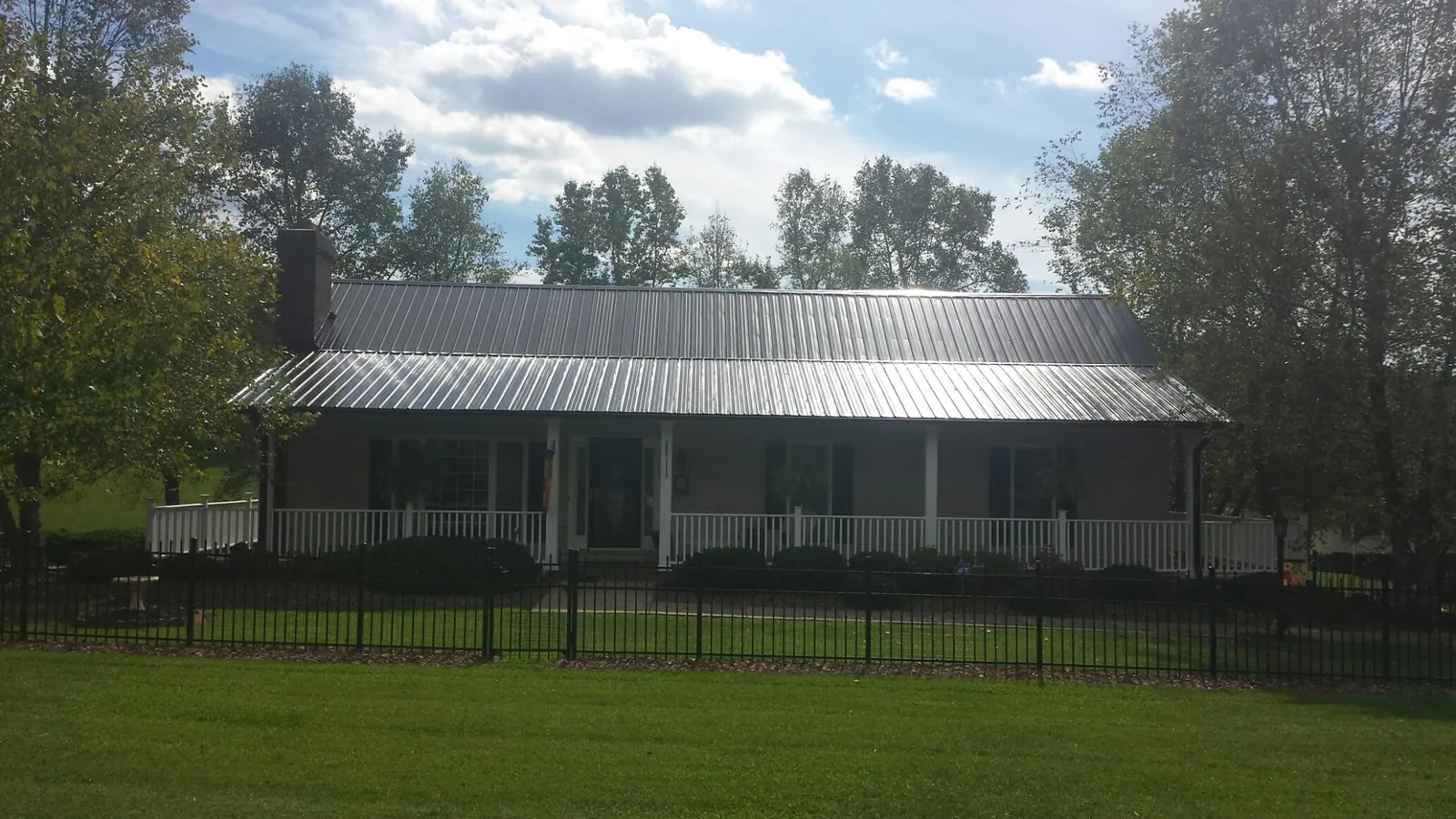 Gray metal roof on a brick ranch with a full width front porch — Gutter Guard Installation work by our crew in Cowan