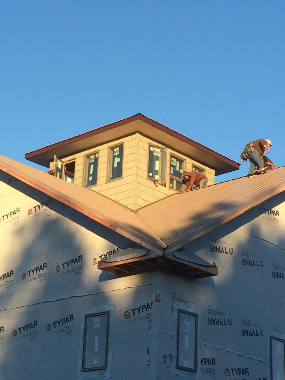 Roofers working around a rooftop cupola on a new metal roof at sunset — Roof Waterproofing in Cowan by Roofing Brothers